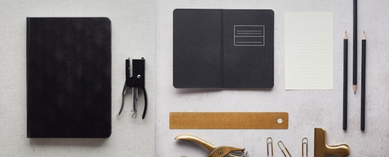 A collection of office supplies, black and white with gold accents, sitting on top of a light gray background.