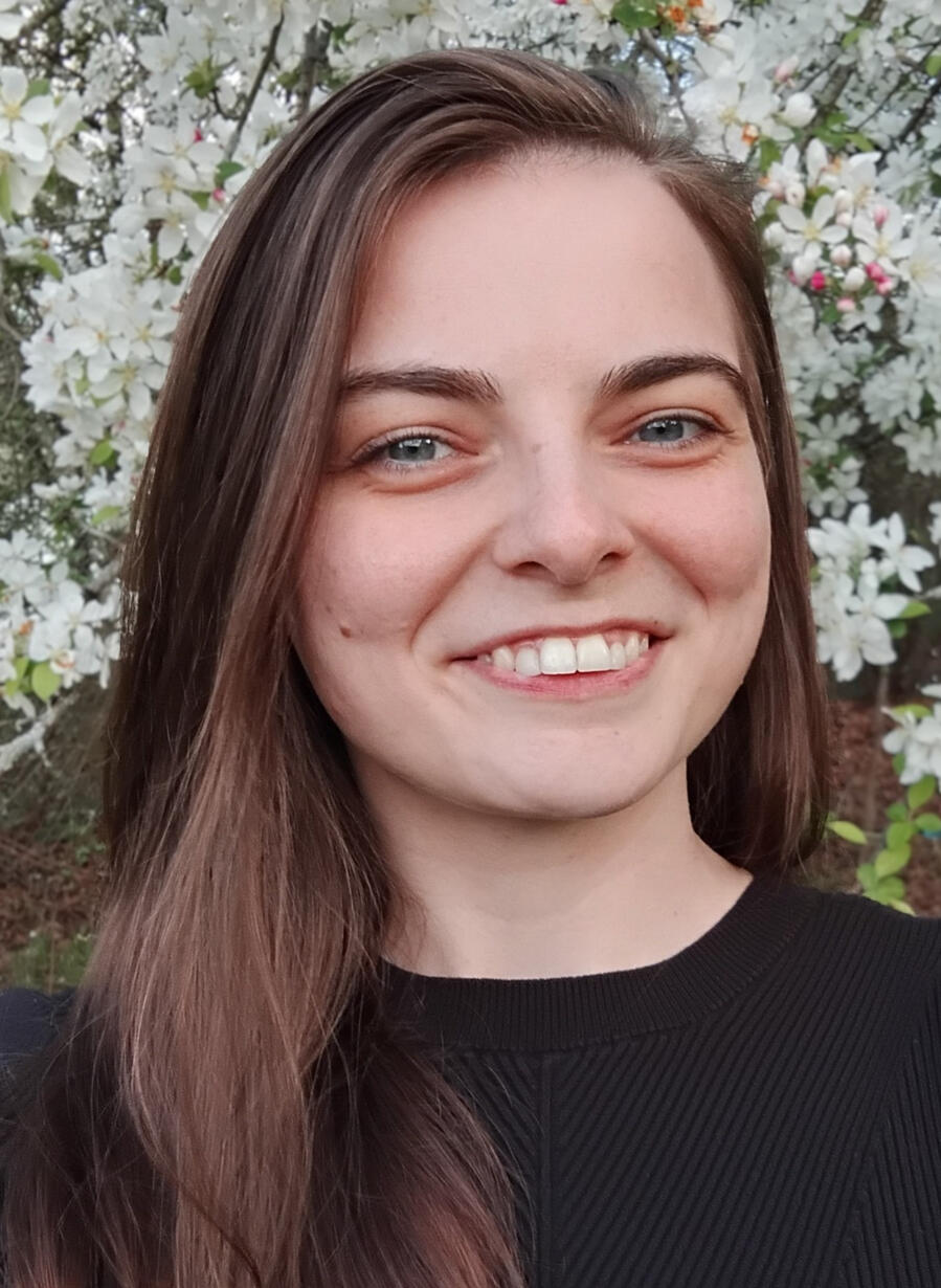A close up headshot of Cara Mawson, founder of Engineering Solutions for Divergent Minds. She is outside, smiling in front of flowers.